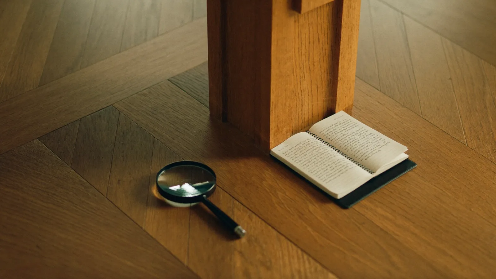 Sol en parquet de chêne, loupe et carnet d'inspection posés sur le bois dans une lumière dorée