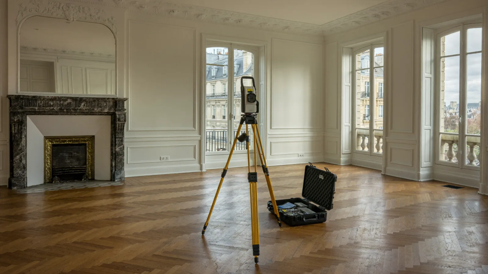 Salon d'un appartement haussmannien vide avec un télémètre laser sur trépied, prêt pour un diagnostic immobilier